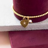  Gold heart and perl charm bracelet round a Burgundy bracelet holder