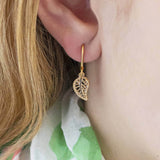 Image shows model wearing gold leaf filigree earrings