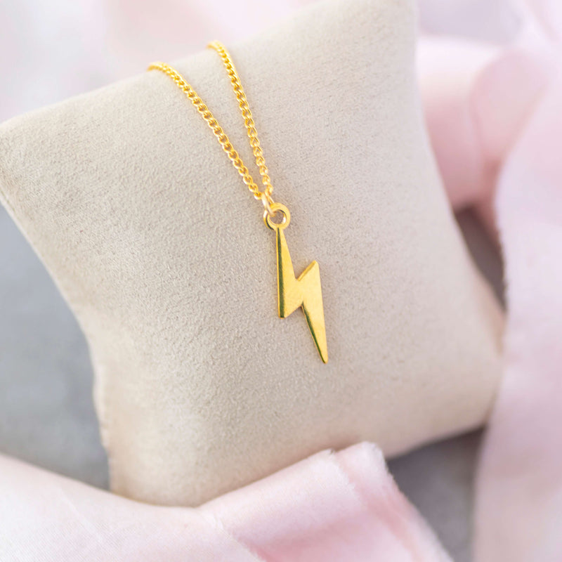 Image shows Gold Lightning Bolt Necklace im a jewellery pillow