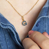 Image shows model wearing gold birthstone initial necklace with initial D and September birthstone