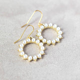 Gold pearl sunburst earrings lying on grey background