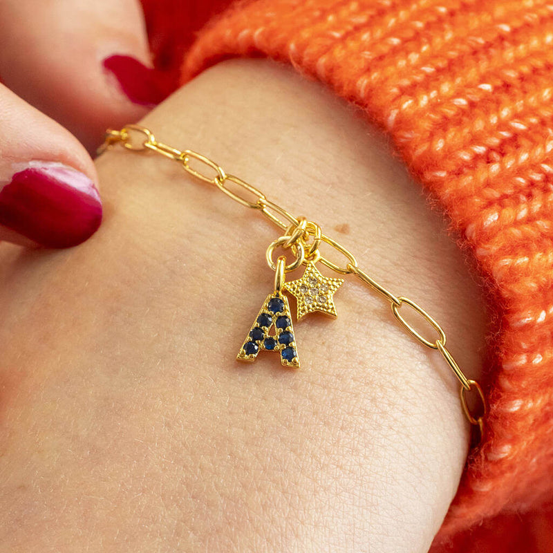 Model wearing gold plated charm bracelet with September birthstone initial And star charm added