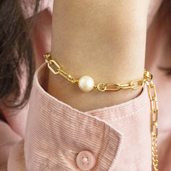 Model wears gold plated chunky chain pearl bracelet  wearing a pink cord shirt