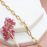 Gold plated chunky chain pearl bracelet  draped over 2 white hexagon coasters with dark pink dried flower next to it