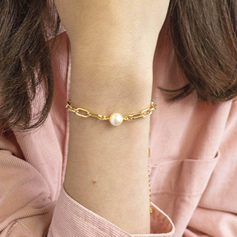 Model wears gold plated chunky chain pearl bracelet wearing a pink cord shirt