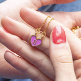 Image shows model holding gold plated enamel heart initial necklace with the initial S
