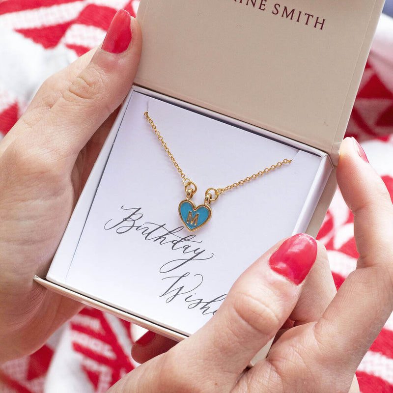 Image shows model holding gold plated enamel heart initial necklace with the initial M in gift box  on a birthday wishes sentiment card