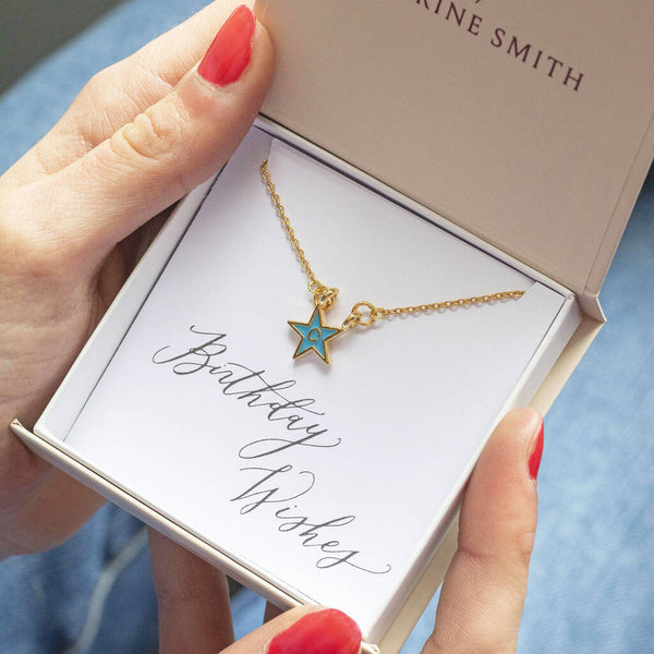 Image shows model holding gold plated enamel star necklace  with initial C in a gift box on a birthday wishes sentiment card