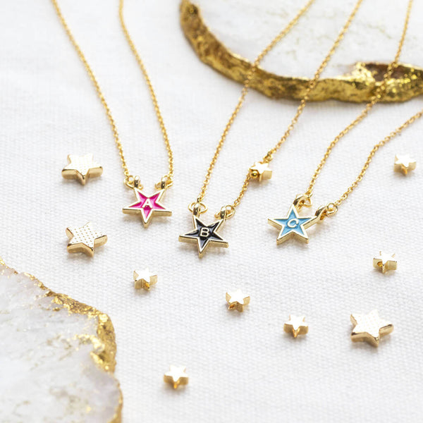 Images shows a selection of gold plated enamel star initial necklaces