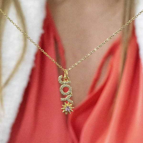 Image shows model holding Gold Plated JOY Necklace with Sun Detail