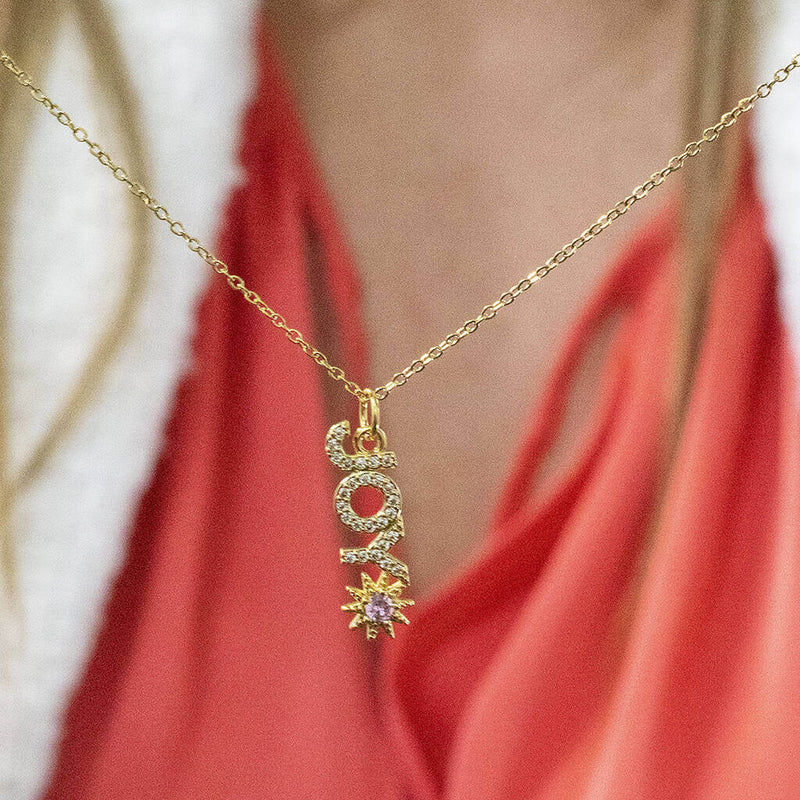 Image shows model holding Gold Plated JOY Necklace with Sun Detail