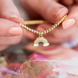 Image shows model holding gold plated pastel rainbow beaded bracelet