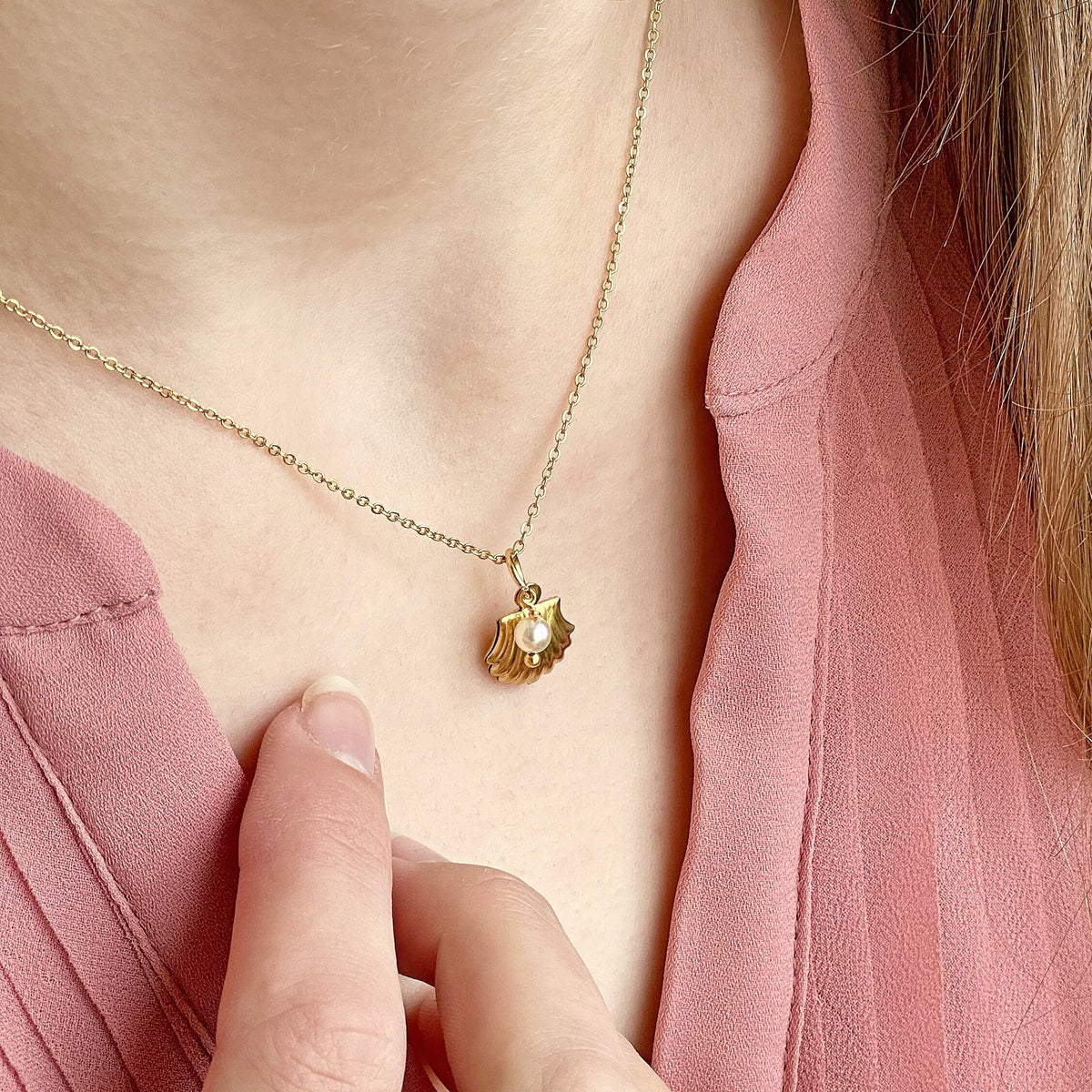 Image shows modela wearing a gold plated oyster shell necklace with pearl charm detail
