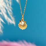 Image shows a gold shell and pearl necklace on a bright blue background