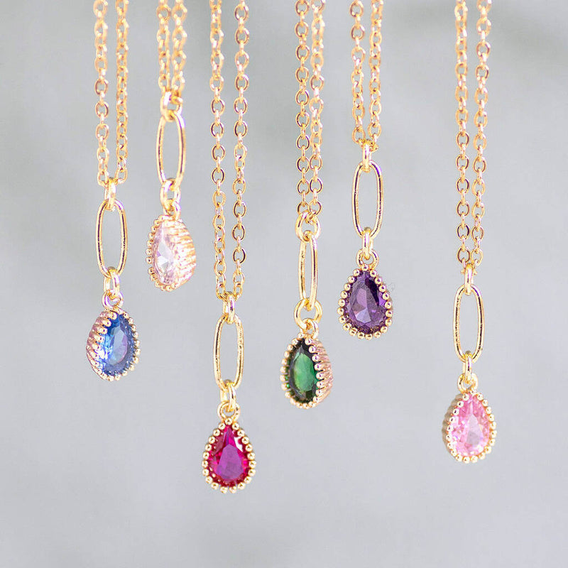 Image shows a selection of Gold Plated Teardrop Birthstone Pendant Necklaces hanging
