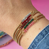 Image shows model wearing a selection of Gold Plated Tiny Birthstone Bar Bracelets