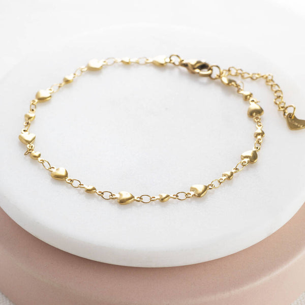 Image shows gold plated graduated hearts anklet on a white backdrop.