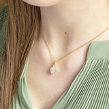Model wears a green top and Gold rhombus pearl pendant necklace