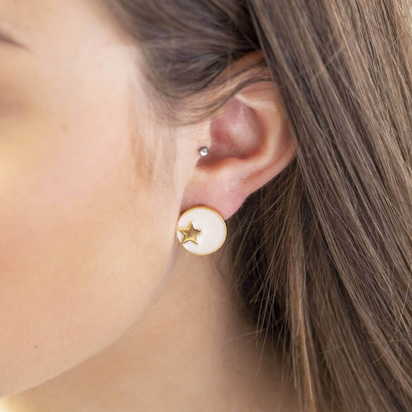 Image shows model wearing gold star circle stud earrings in ivory