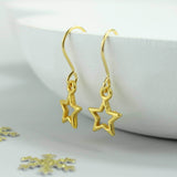 Image shows gold star earrings hanging from a white bowl 