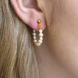 Model wears handmade beaded pearl Huggie hoop earring