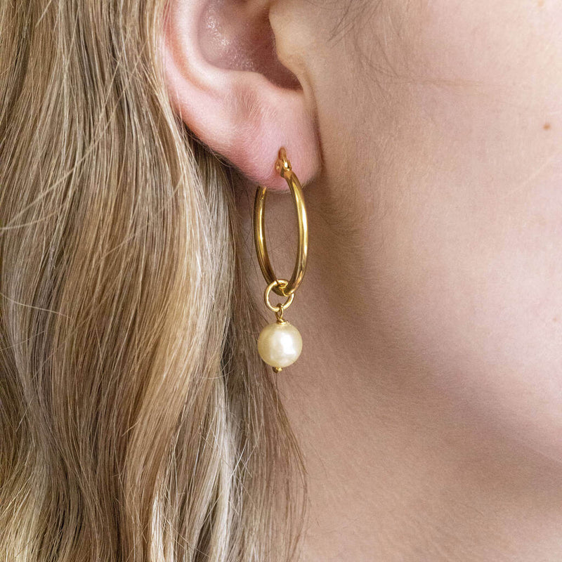 Model wears hinged hoop earring with Swarovski pearl detail