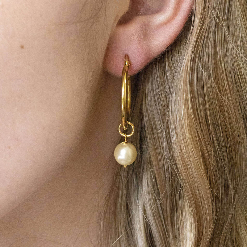 Model wears hinged hoop earring with Swarovski pearl detail  