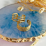 Image show adjustable triple band gold rings on a blue glass background