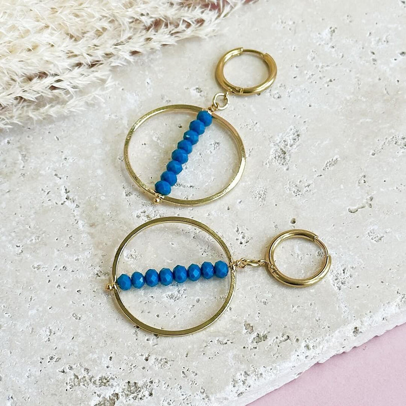 Image shows Indigo Beaded Stack Crystal Earrings lying on a stone slab