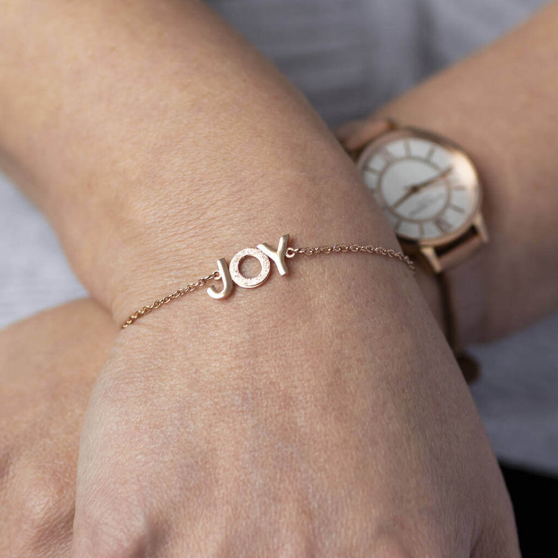 Image shows model wearing rose gold JOY positive affirmation bracelet