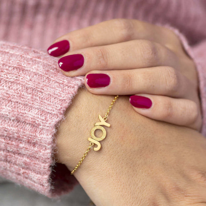 Image shows model wearing gold JOY positive affirmation bracelet