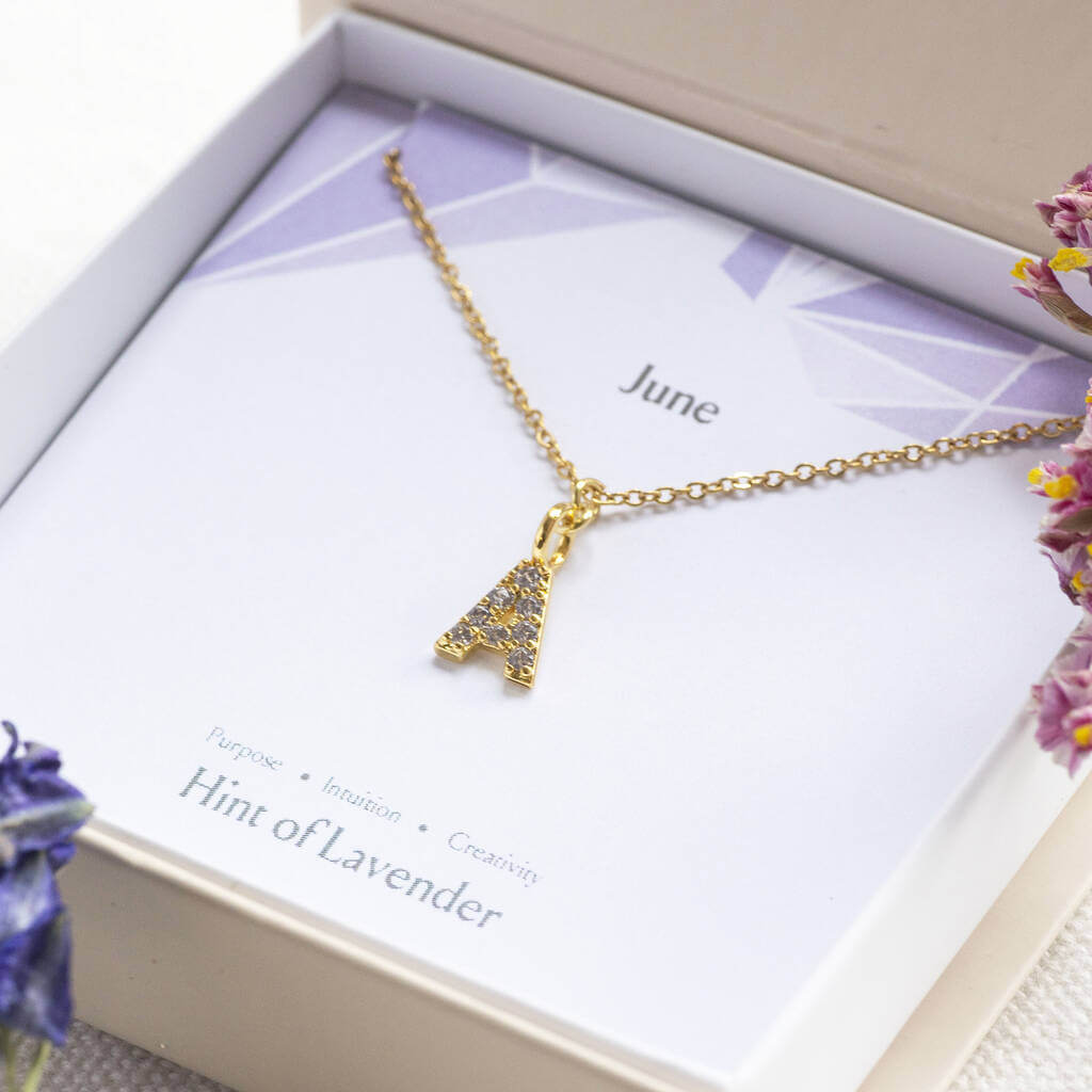 Image shows June birthstone initial necklace in a gift bow on a birthstone characteristic card
