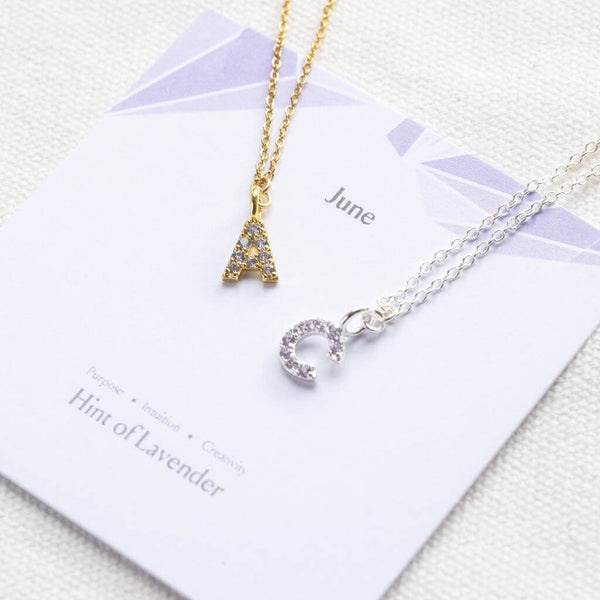 mage shows gold and silver June birthstone initial necklaces on a birthstone characteristic card