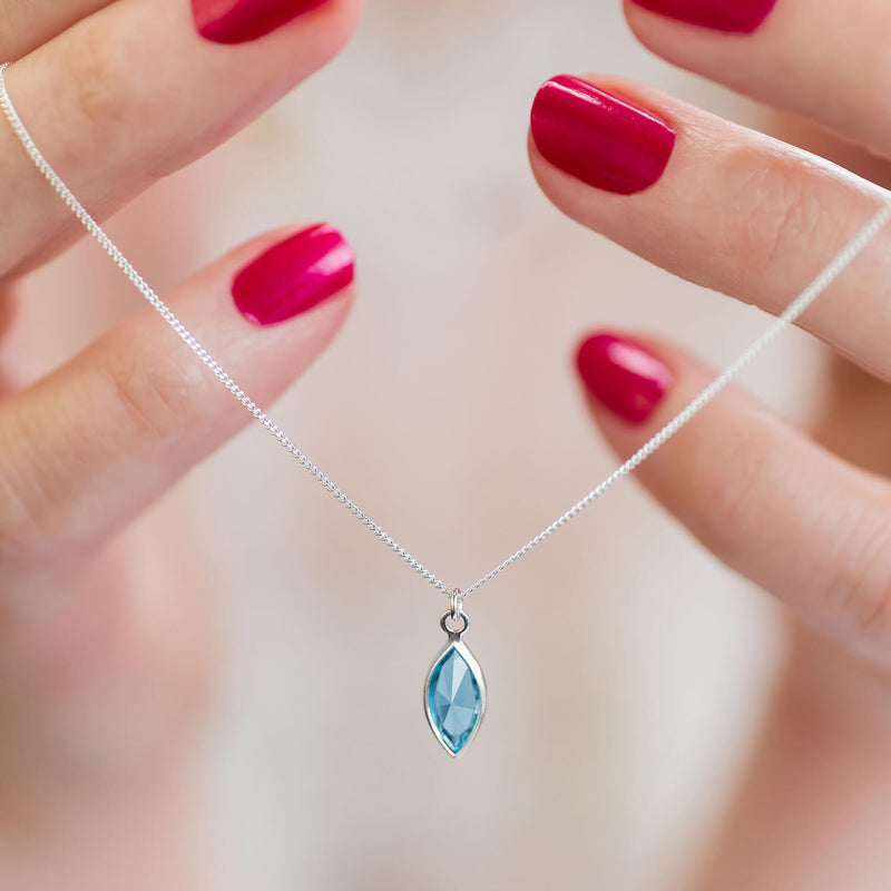 Image shows model holding silver Marquise Swarovski Crystal Birthstone Pendant Necklace with March birthstone
