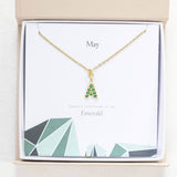 Image shows gold May birthstone emerald initial necklace in a gift box on a May birthstone characteristics card