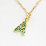 Image shows a close upon of May birthstone emerald initial necklace