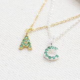 Image shows gold and silver May birthstone emerald initial necklace