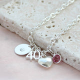 Image shows milestone birthday personalised charm bracelet with initial disc D, number 40, Heart charm and Rose birthstone