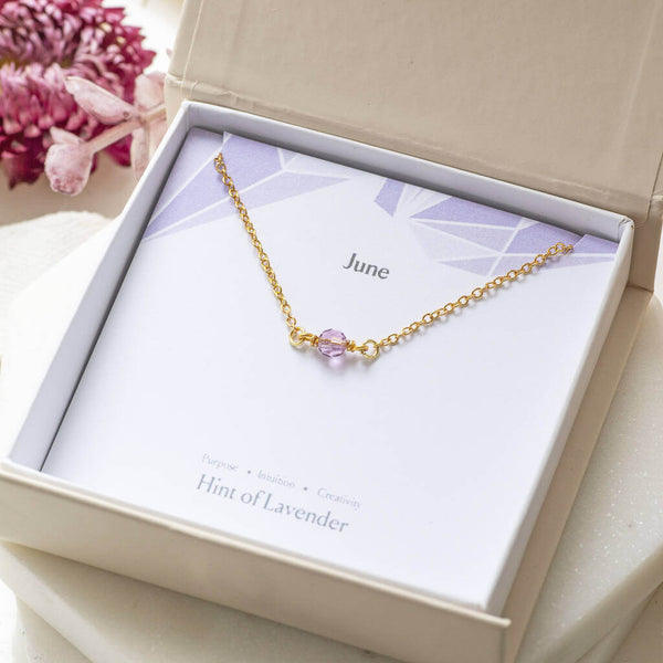 Image shows gold Minimalist June Birthstone Single Bead Necklace in a gift box on a June birthstone characteristic card 