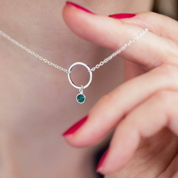Image shows model holding Minimalist Silver Circle Birthstone Charm Necklace with May birthstone