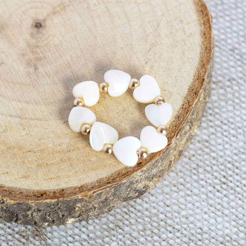 Mother of pearl heart stretch ring lying on a wooden circle