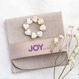 Mother of pearl heart stretch ring lying on a  JOY suede pouch