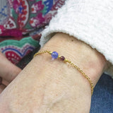 Image shows model wearing gold Mother and Child Beaded Birthstone Chain Bracelet with September and February birthstone