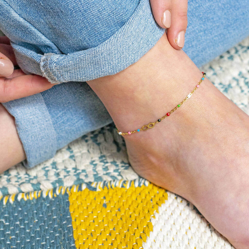 Model wears  dainty multicoloured beaded infinity anklet with tiny infinity charm. Multi coloured beads are random - pictured from left to right: red, green, white, pink, blue and black.