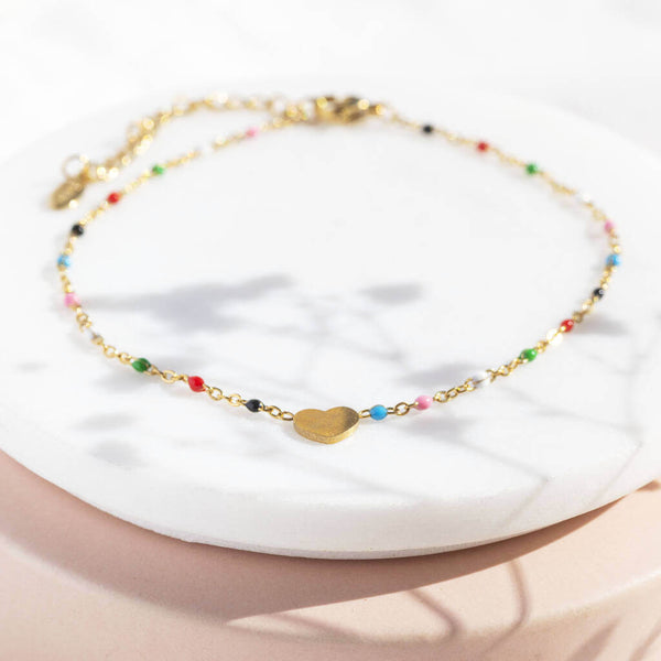 Image shows gold plated multi coloured beaded heart anklet on a white backdrop.