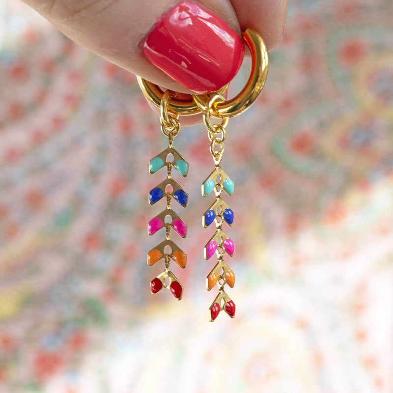 image shows hand holding multi coloured spiky chain huggie earrings