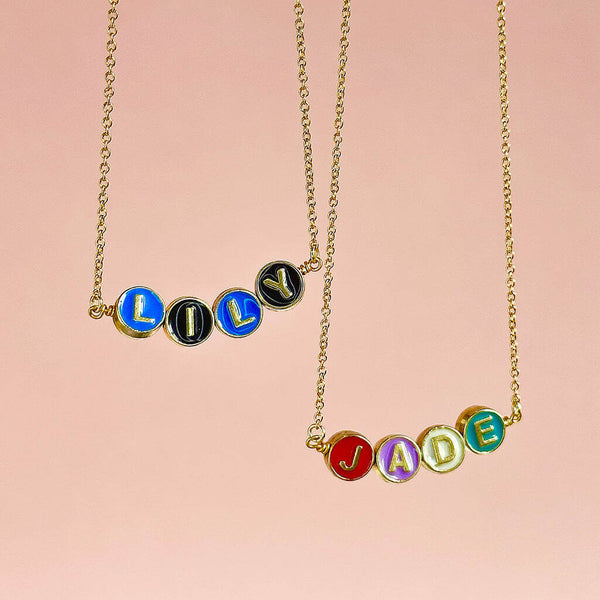 Image shows two hanging personalised enamel disc name necklaces with the names Lily and Jade