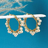 Images shows Ornate Pearl Wrapped Hoop Earrings hanging from a white pole with a blue background