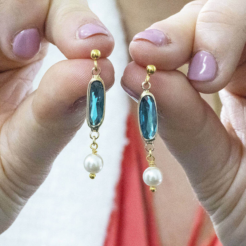 Image shows model holding Oval Birthstone Earrings with Pearl Detail with December birthstone