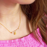 Model wears pearl bar and initial charm necklace with the initial B 